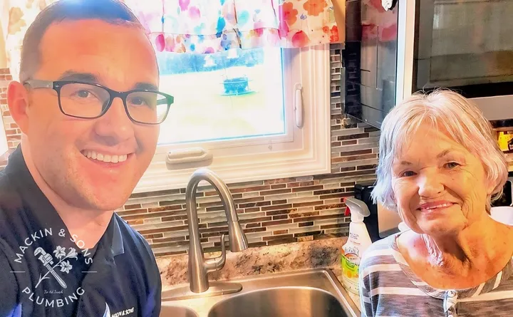A Mackin & Sons plumber with Protect member Virginia H. at her kitchen sink after a service visit